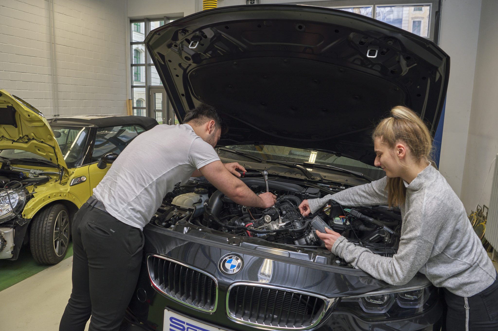 Auszubildende arbeiten gemeinsam an einem Fahrzeug in der KFZ-Werkstatt